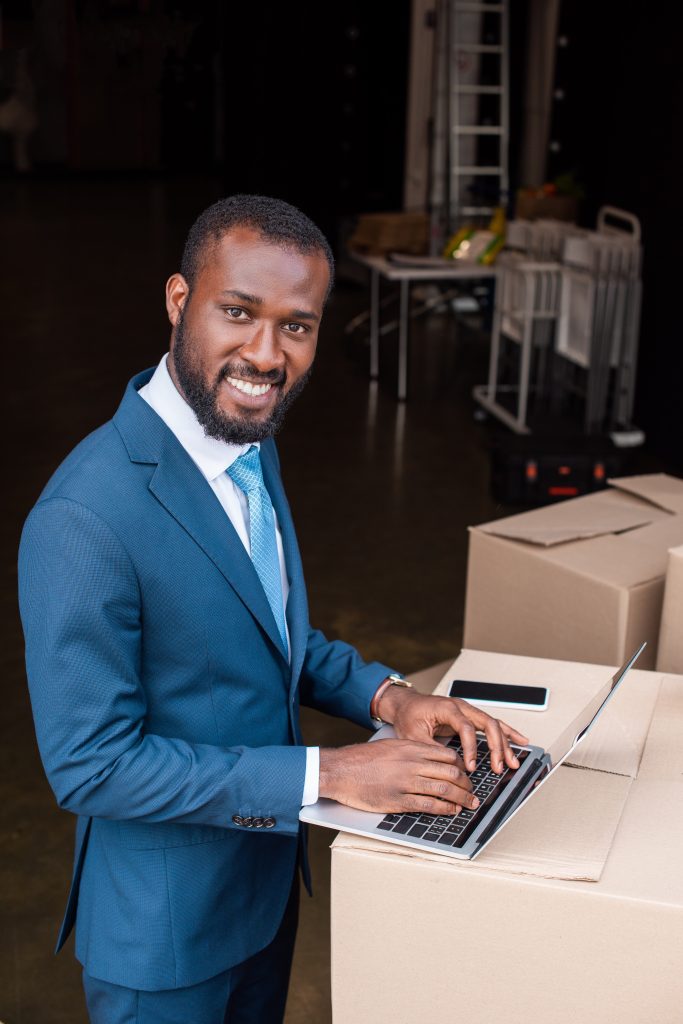 Businessman using a laptop beside packaged stock