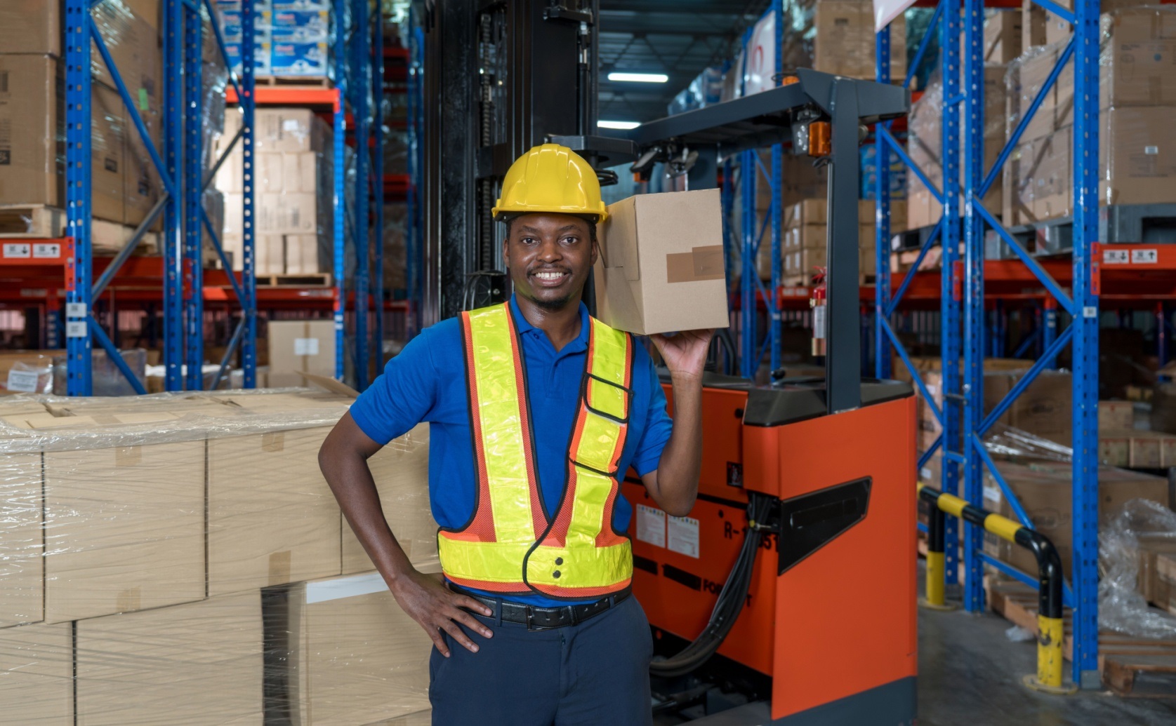 Warehouse worker holding a box beside storage racks.