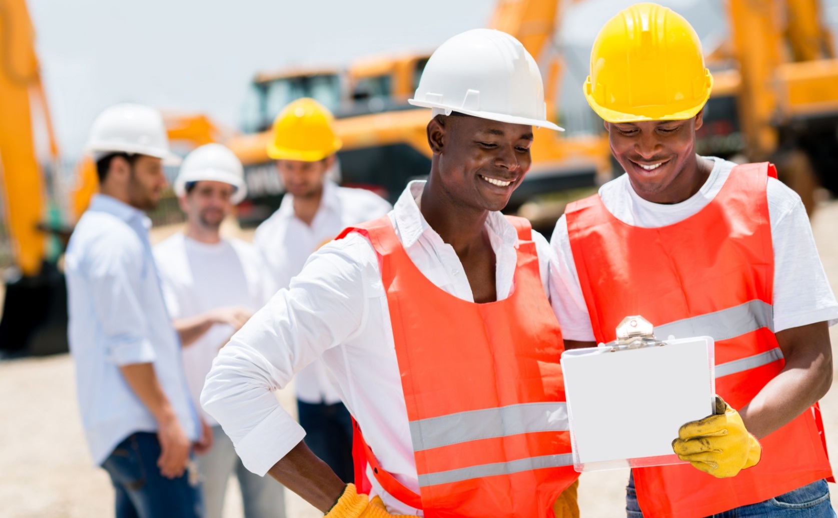 Two construction workers reviewing a clipboard at a building site.