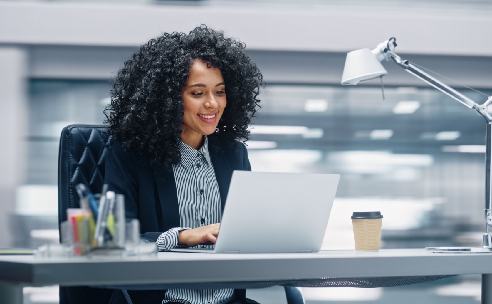 Woman working on a laptop at an office desk.