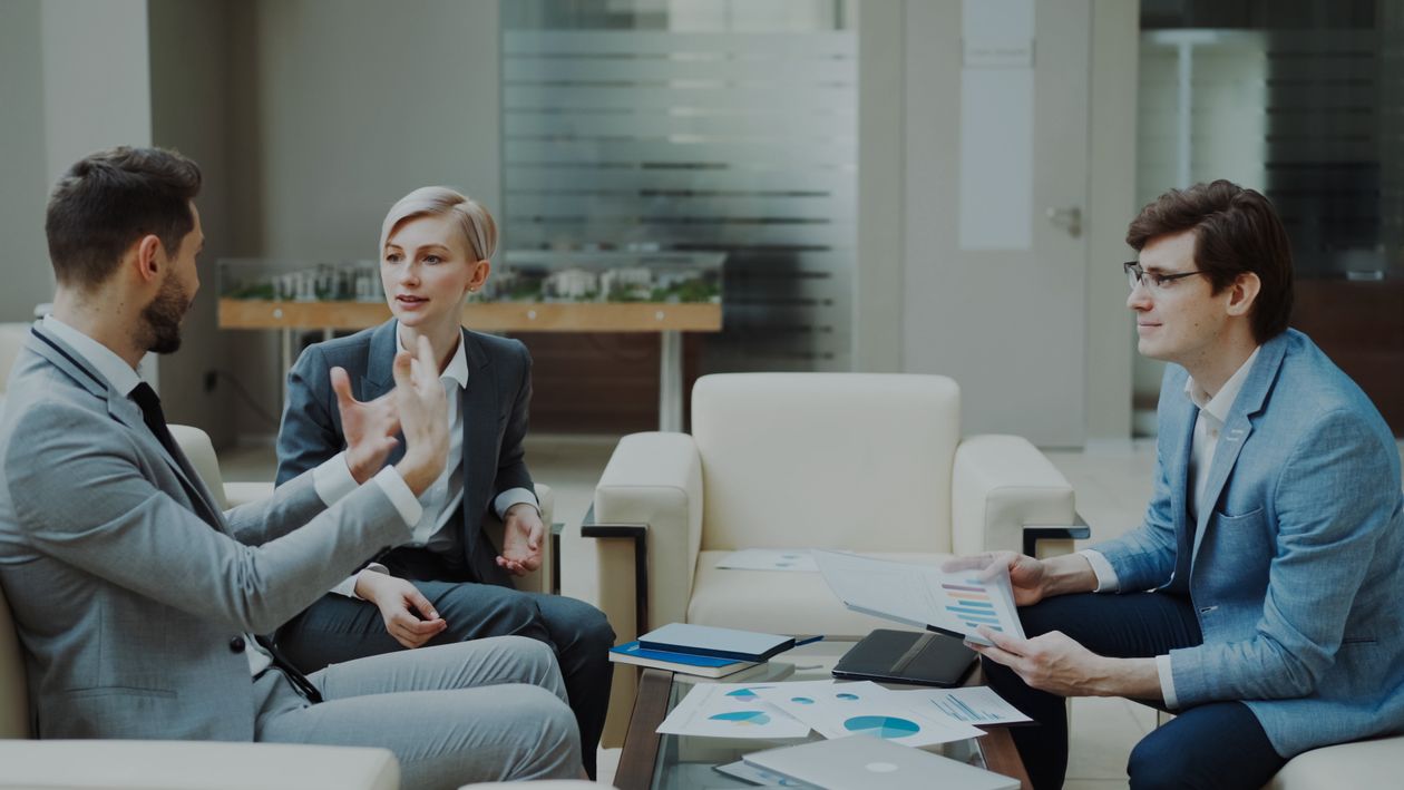 Three professionals discussing charts and documents in an office.
