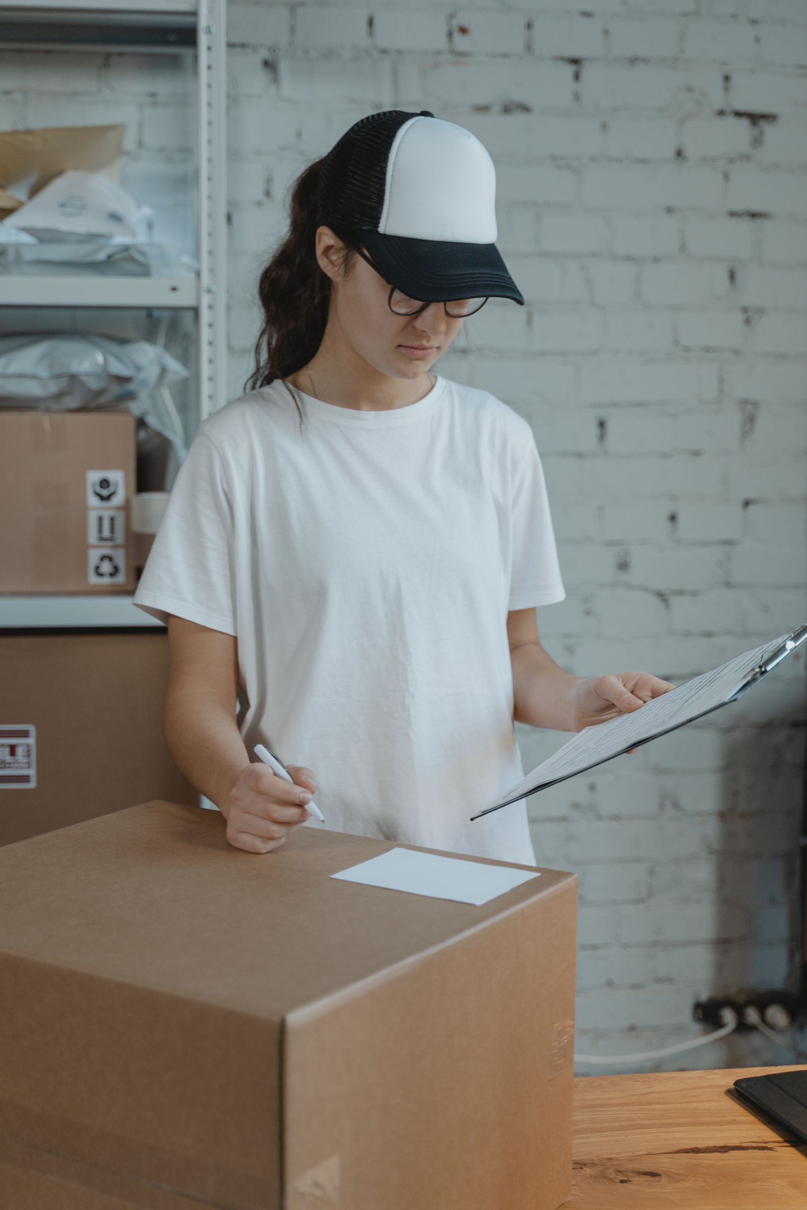 Warehouse worker checking a clipboard and labelling a box