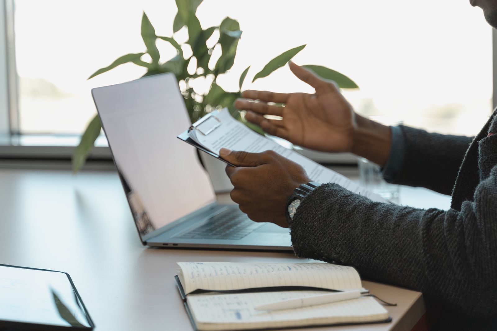 Professional reviewing documents beside a laptop and notebook