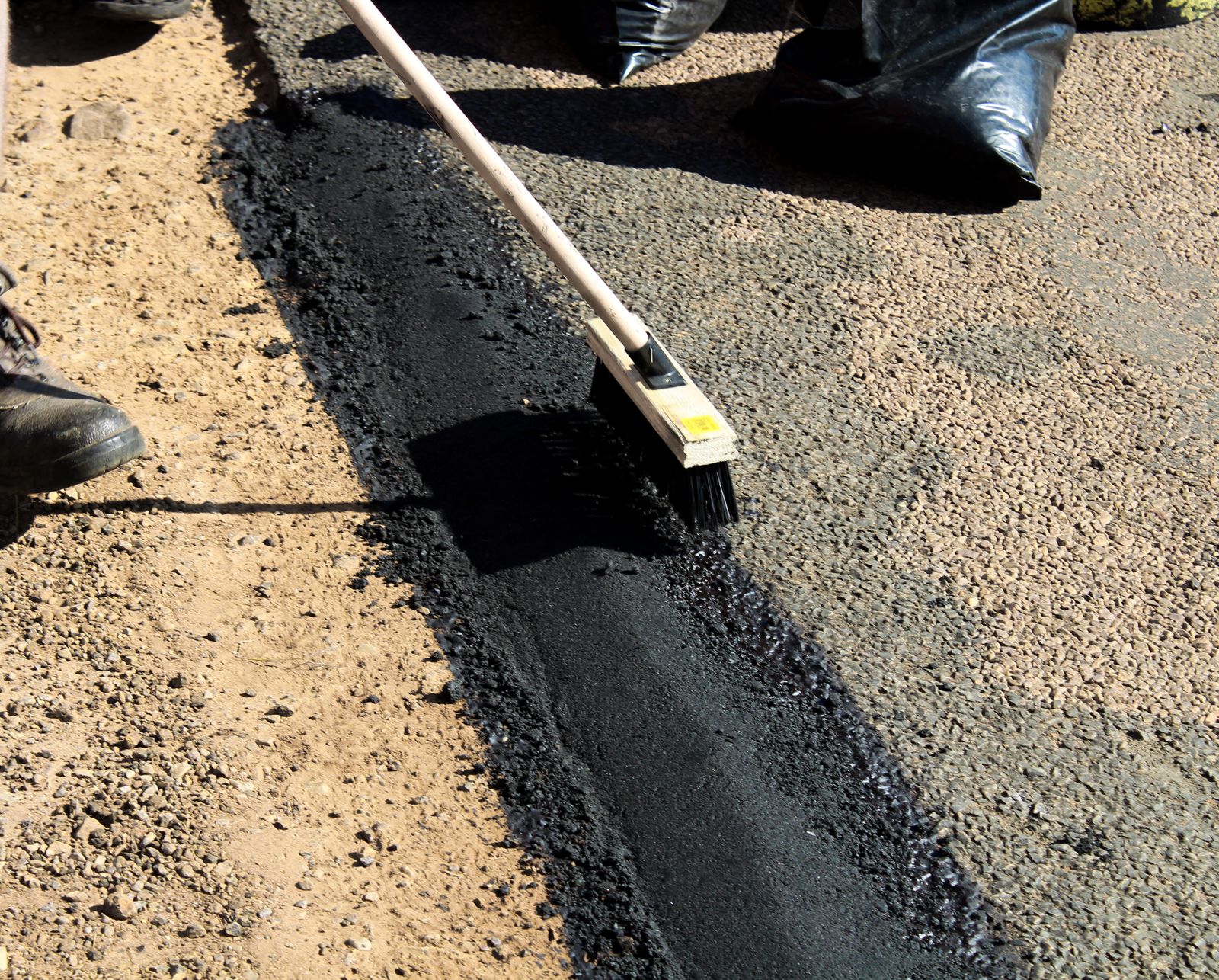 Worker sweeping freshly laid concrete on a road